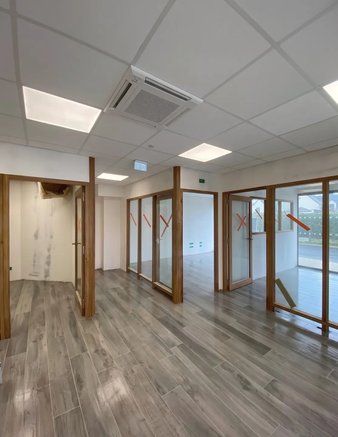 Bureaux aux cloisons vitrées, sol en carrelage imitation parquet