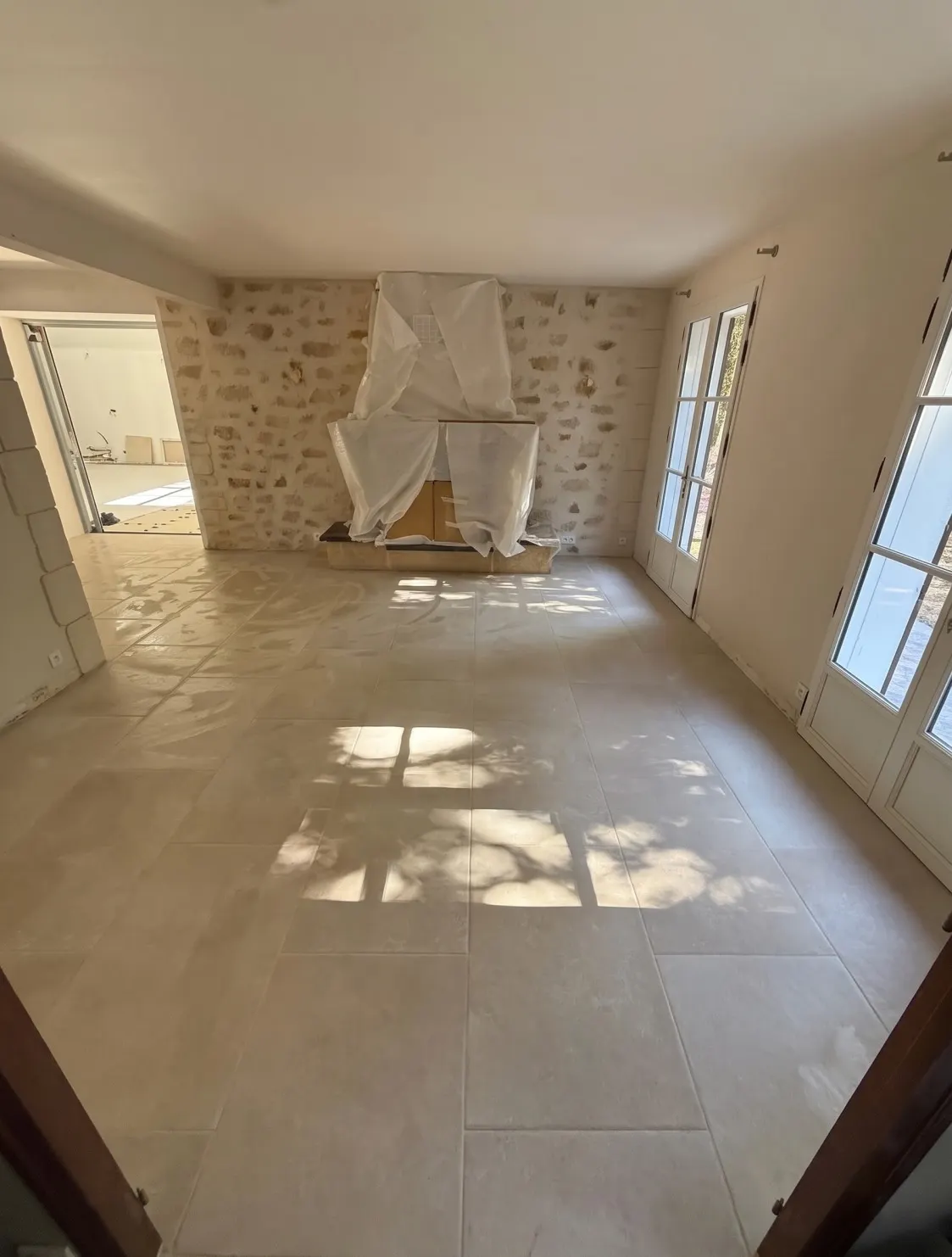 Séjour carrelé en grands carreaux beiges clairs, lumière du soleil au sol